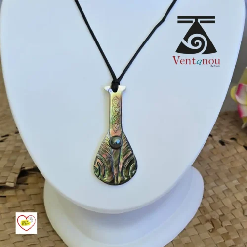 collier-pour-homme-en-nacre-et-perle-noire Pendentif polynésien en forme de rame paddle, en nacre de Bora Bora et perle noire, présenté sur cordon noir. Pendentif Polynésien Rame en Nacre de Bora Bora et Perle Noire
